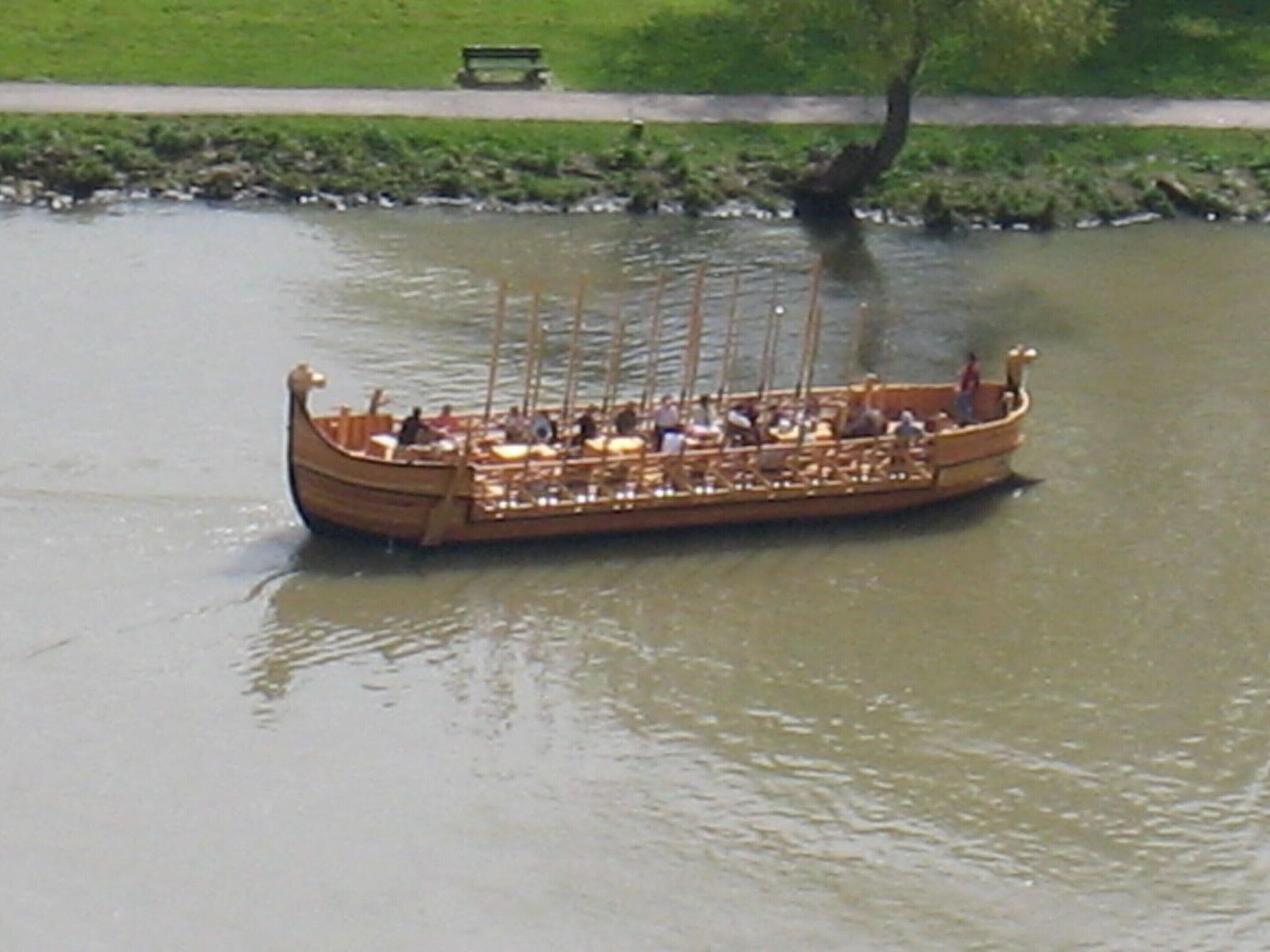 A wooden boat with passengers, floating on a body of water.