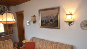 Ein gemütliches Wohnzimmer mit Holztisch, gestreifter Couch und zwei Wandleuchten.