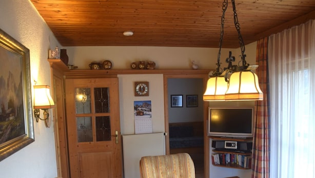 Ein gemütliches Wohnzimmer mit Holzboden, einer Couch, einem Tisch und einem Fernseher in der Ecke.