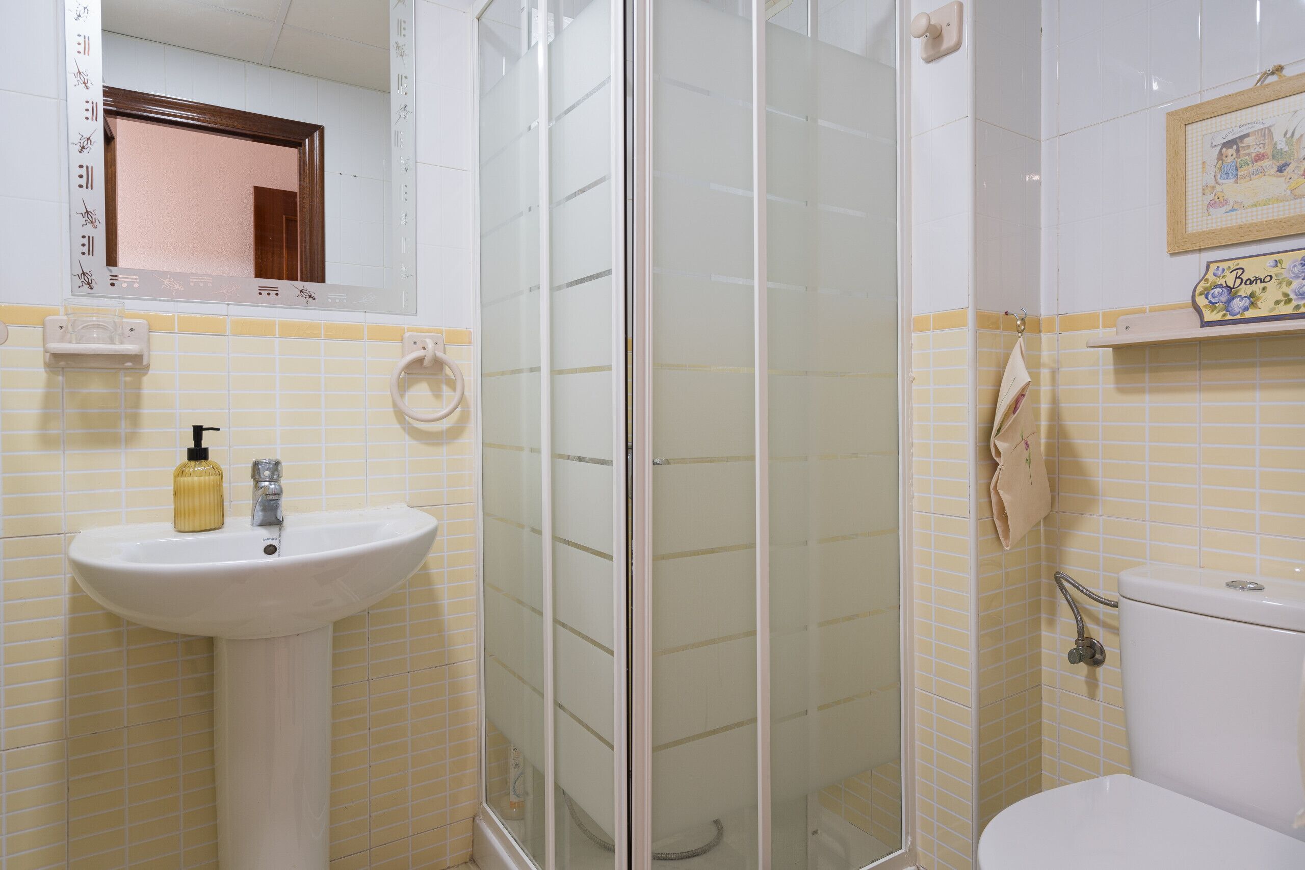 A bathroom with a white sink, a glass shower enclosure, and a toilet.