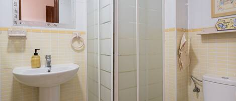A bathroom with a white sink, a glass shower enclosure, and a toilet.