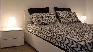 A modern bedroom with a bed, two bedside tables, and a ceiling light.
