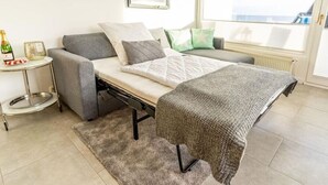 Ein gemütliches Schlafzimmer mit Bett, Nachttisch, Heizkörper und Fenster mit Blick.