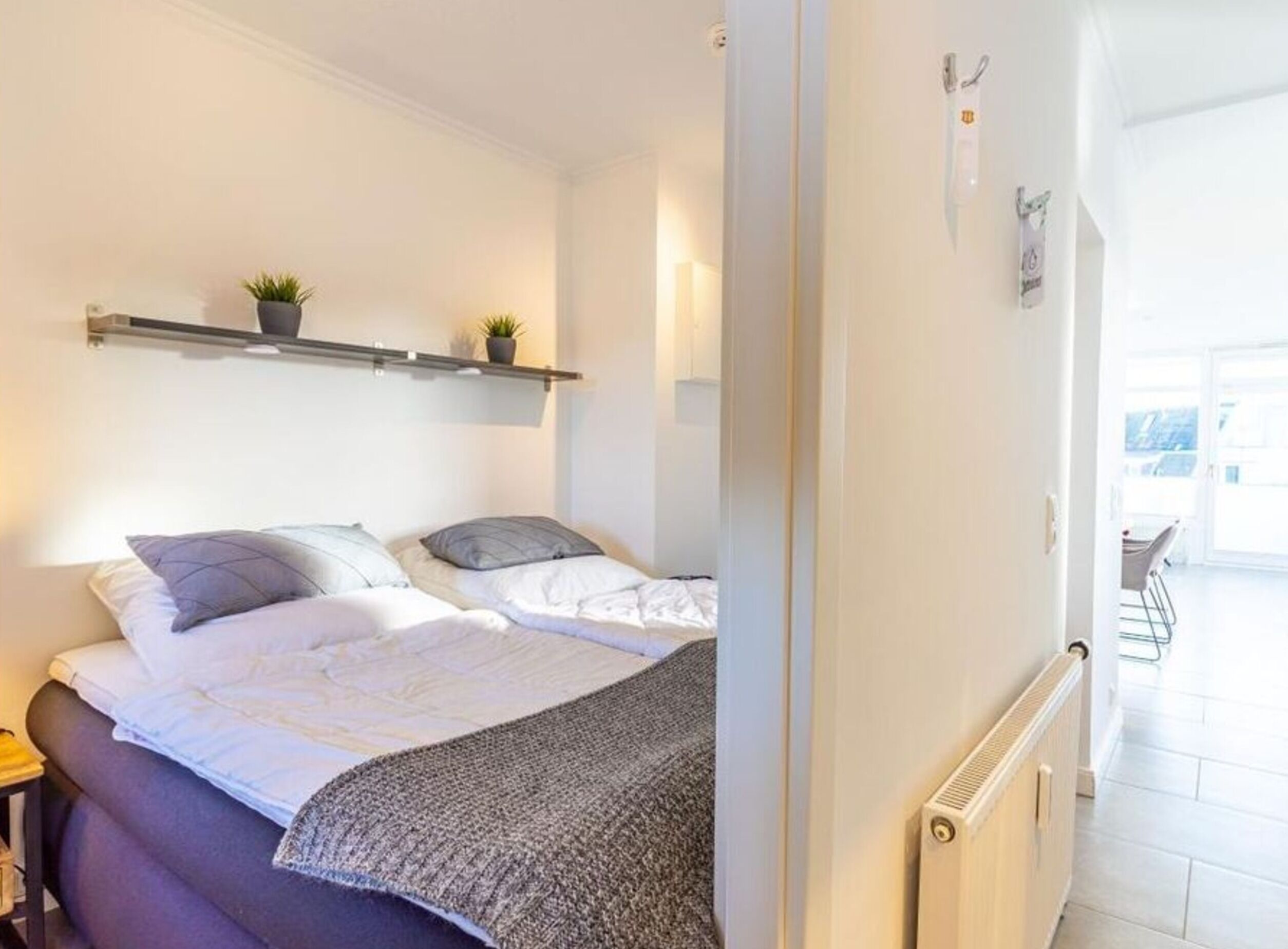Une chambre à coucher avec un lit, des tables de chevet, un radiateur et une fenêtre.