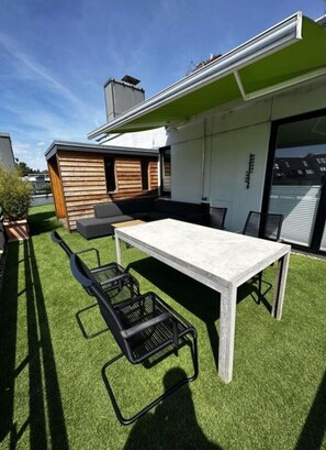 A modern outdoor patio with a dining table, chairs, and a small seating area. - 2-room Luxury Apartment (Scharbeutz)