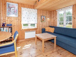 A cozy cabin interior with a wooden interior, a blue sofa, a dining table with chairs, and a bookshelf. - 6 Person Holiday Home in Fur (Fur)