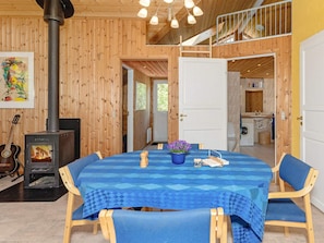 Un interior de madera con una mesa de comedor, sillas, una estufa y una zona de cocina.