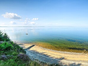 A calm lake with a boat, clear skies, and a pebble beach. - 6 Person Holiday Home in Fur (Fur)