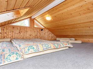 A cozy attic bedroom with a sloped ceiling, a bed with patterned bedding, and a single wall-mounted light fixture. - 6 Person Holiday Home in Fur (Fur)