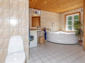 Une salle de bain équipée d’un lave-linge, d’une baignoire et d’une fenêtre.