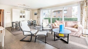 A modern living room with a sofa, chairs, a coffee table, and a dining area with a table and chairs. - Apartment Near Koksijde Beach With Terrace (Koksijde)