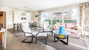 A modern living room with a sofa, chairs, a coffee table, and a dining area with a table and chairs. - Apartment Near Koksijde Beach With Terrace (Koksijde)