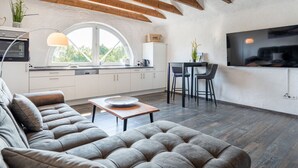 A modern interior with a loft-style ceiling, a sofa, a dining area, and a kitchen. - No. 7 Lake View Modern Retreat (Aurich)
