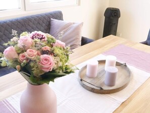 En stue med sofa, sofabord med blomster og stearinlys.