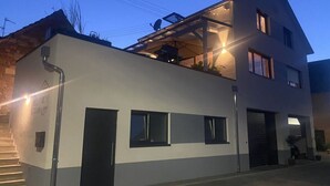 Un bâtiment moderne à deux étages, doté d’un toit plat, de grandes fenêtres et d’une antenne parabolique bien visible.