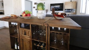 Une cuisine avec un îlot central en bois, des verres à vin et une pastèque posée sur le comptoir.