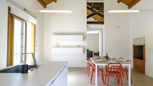 A modern kitchen with a white countertop, red chairs, and a brick oven.