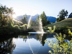 A tranquil lake with a fountain, surrounded by lush greenery and mountains in the background. - Lovely Apartment in Sautens (Sautens)