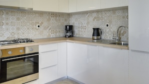 A kitchen with white cabinets, a gas stove, an oven, a coffee maker, and a sink. - Nicely Decorated Apartment With Private Pool (Vodnjan)