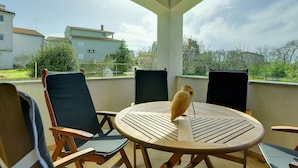 A covered outdoor seating area with a round table and chairs, overlooking a residential neighborhood. - Nicely Decorated Apartment With Private Pool (Vodnjan)