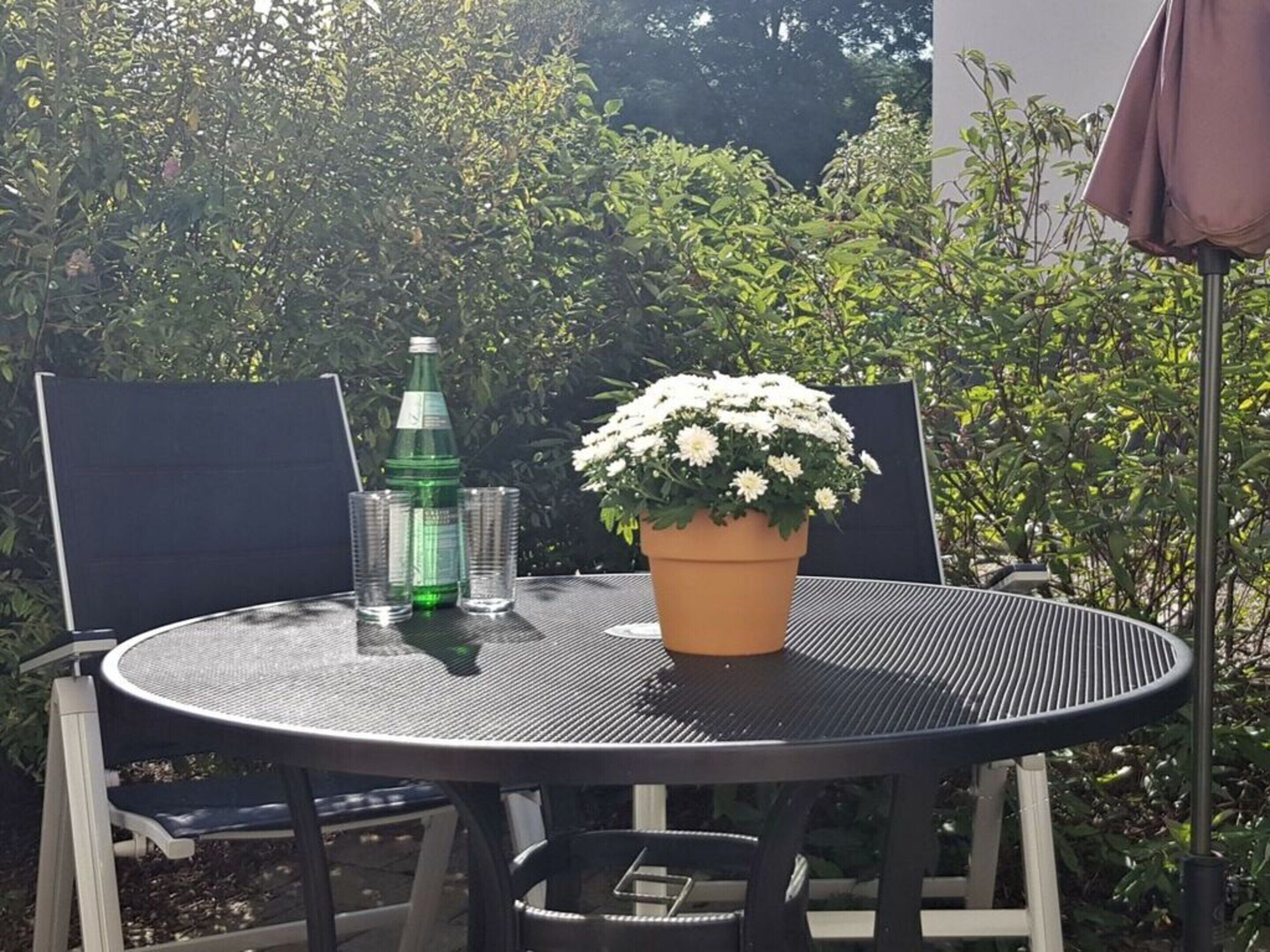 A round metal table with a potted plant and two glasses.