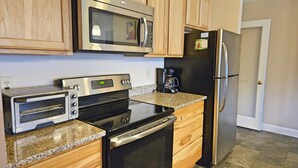 A kitchen with wooden cabinets, a stainless steel microwave, a toaster oven, a coffee maker, and a refrigerator. - 1st floor, FP, mtn & pond view, deck, pool, pet-friendly. F1663 by LRS (Lincoln)