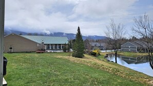 A residential area with a large building, a pond, and a mountain in the background. - 1st floor, FP, mtn & pond view, deck, pool, pet-friendly. F1663 by LRS (Lincoln)