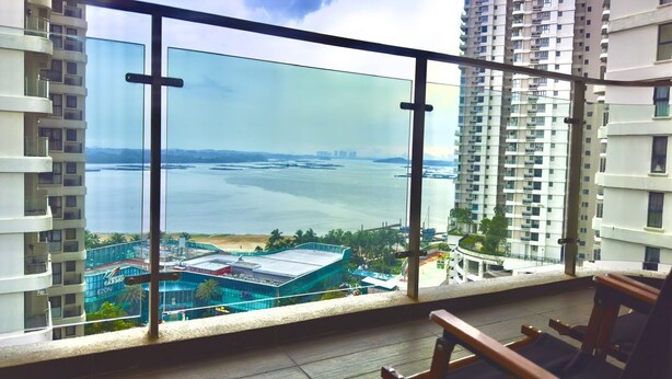 A balcony with a glass railing overlooking a marina and a beach. - JB City DangaBay Shopping Mall Apartment (Johor Bahru)