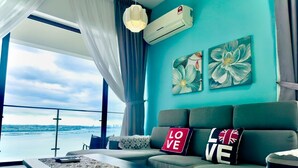 A modern living room with a sofa, a coffee table, and artwork on teal walls. - JB City DangaBay Shopping Mall Apartment (Johor Bahru)