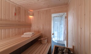 A sauna room with wooden benches, a shower area, and a bucket. - Villa in Zeeland With Outdoor Jacuzzi (Colijnsplaat)