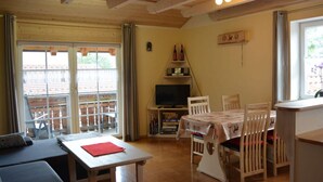 A cozy room with a wooden ceiling, a dining table with chairs, a sofa, and a television on a stand. - Holiday Apartment Schiechtele 2 (Pfronten)