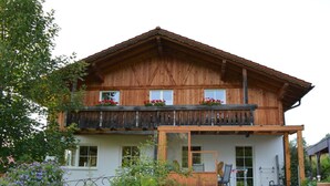 A wooden chalet with a balcony, a covered porch, and a garden with flowers. - Holiday Apartment Schiechtele 2 (Pfronten)