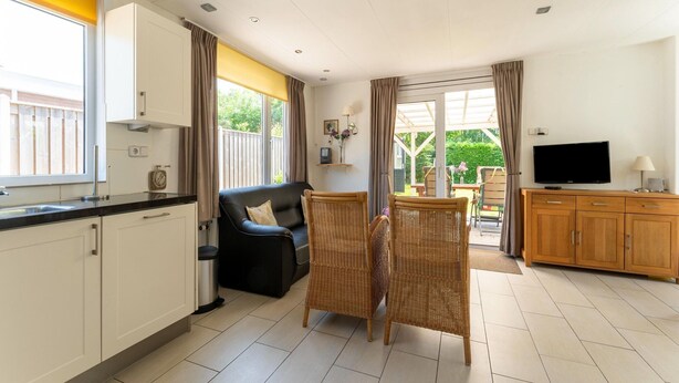 A compact living space with a kitchenette, a sofa, a dining area, and a TV. - Holiday Home in Baarland With Garden (Baarland)