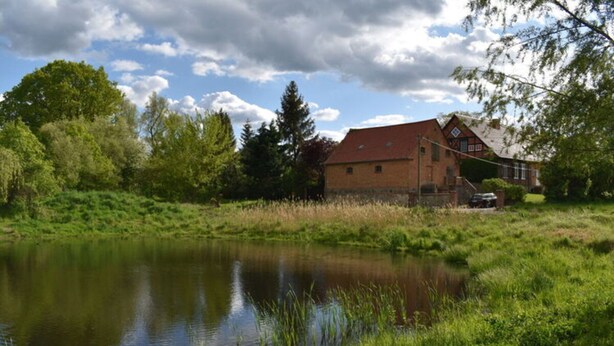 A house with a red roof and a pond in front. - Holiday Apartment in Flieth-stegelitz (Flieth-Stegelitz)