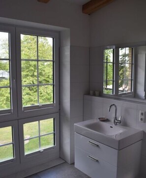 A bathroom with a large window, a sink, and a mirror.