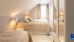 Un dormitorio con dos camas, un armario y una ventana con cortinas.
