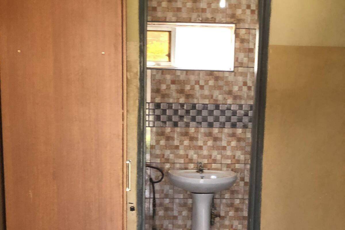 Une salle de bain avec un sol carrelé, un lavabo et une fenêtre située au-dessus.