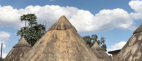 A traditional thatched-roof house with a central dome and smaller conical roofs.