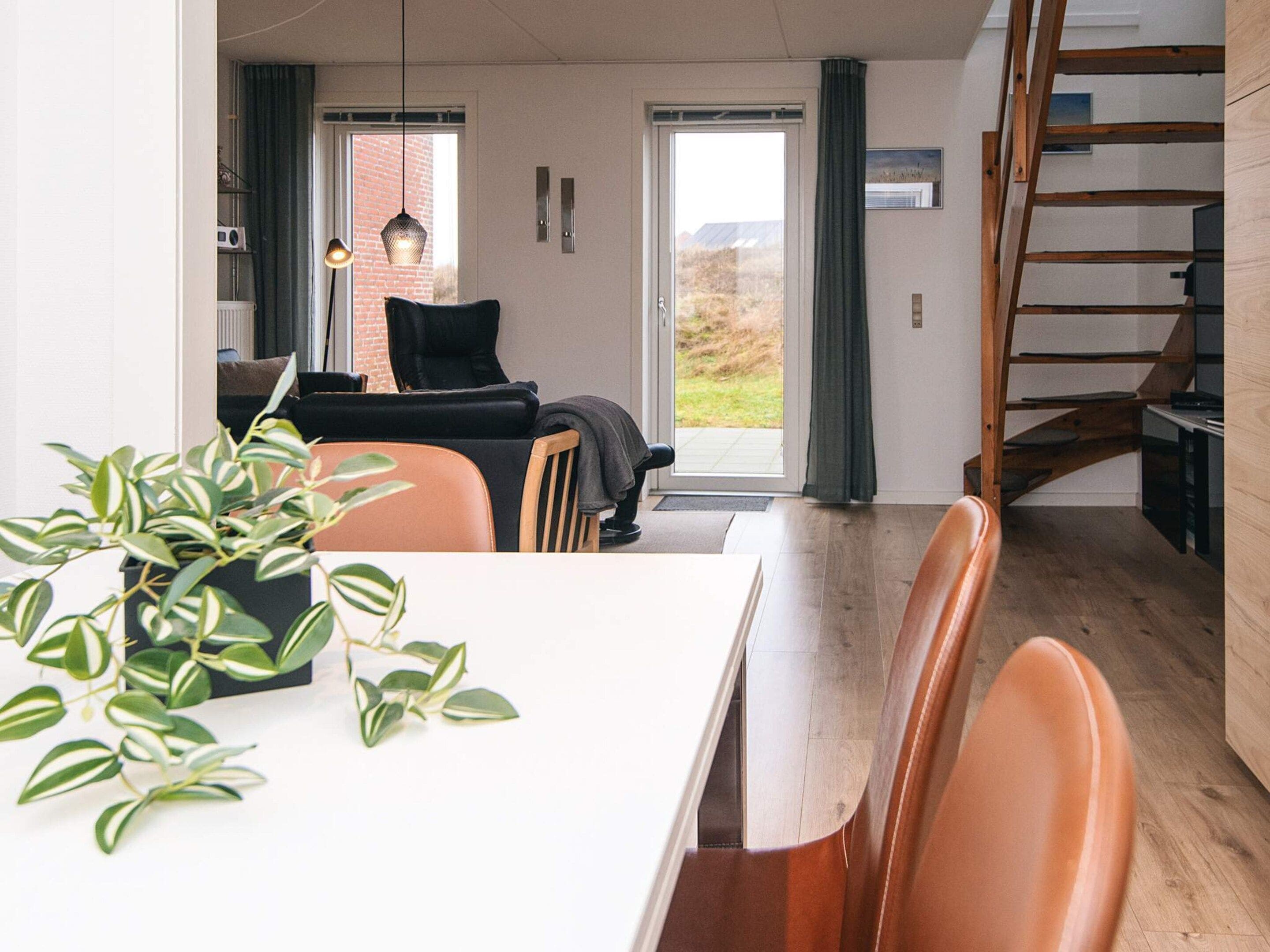 Ein modernes Wohnzimmer mit Essbereich, einer Treppe und Blick ins Freie.