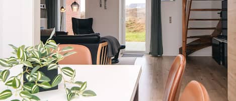 Una sala de estar moderna con comedor, una escalera y vistas al exterior.