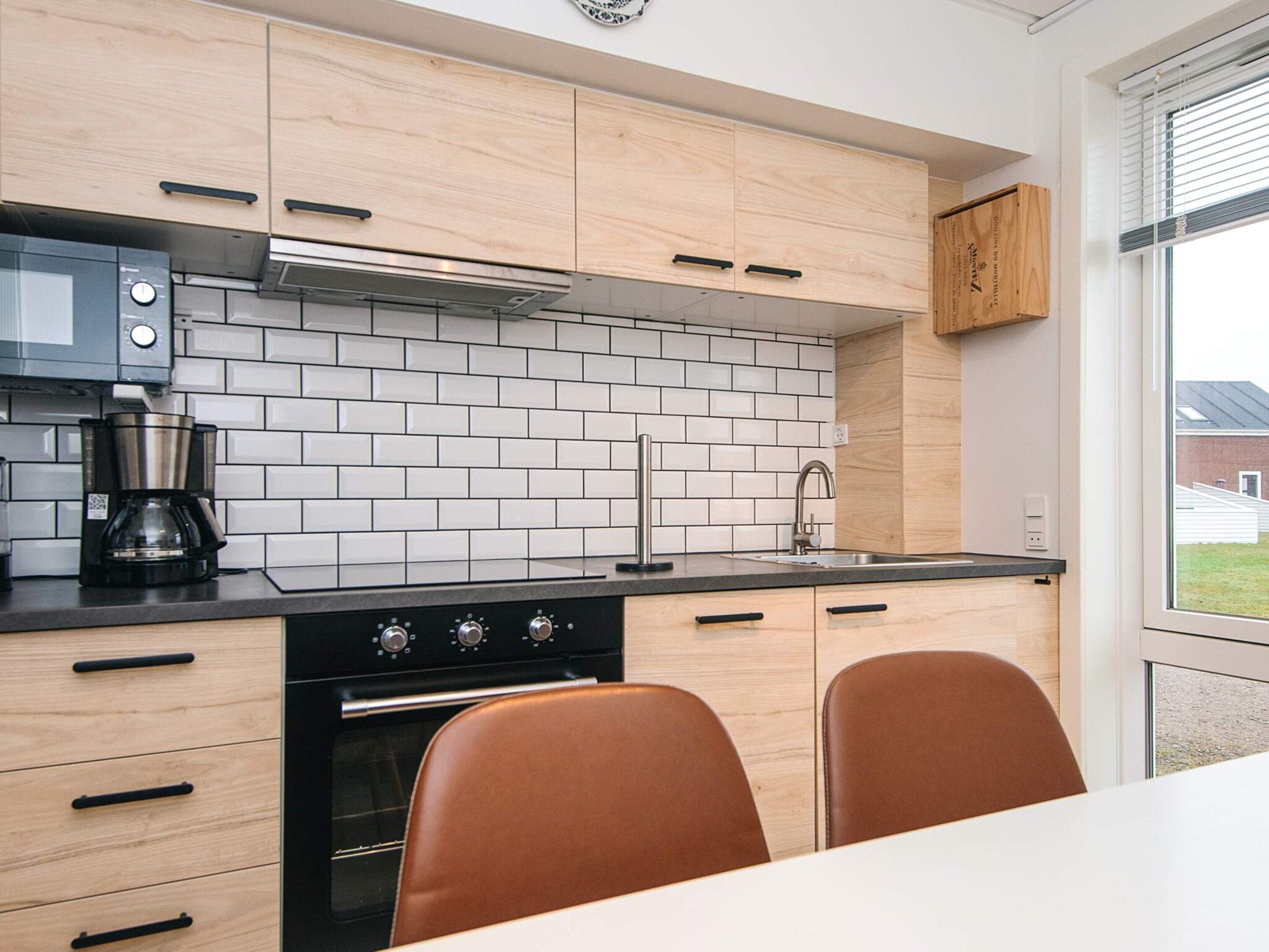 Une cuisine moderne avec un four noir, une machine à café et des armoires en bois.