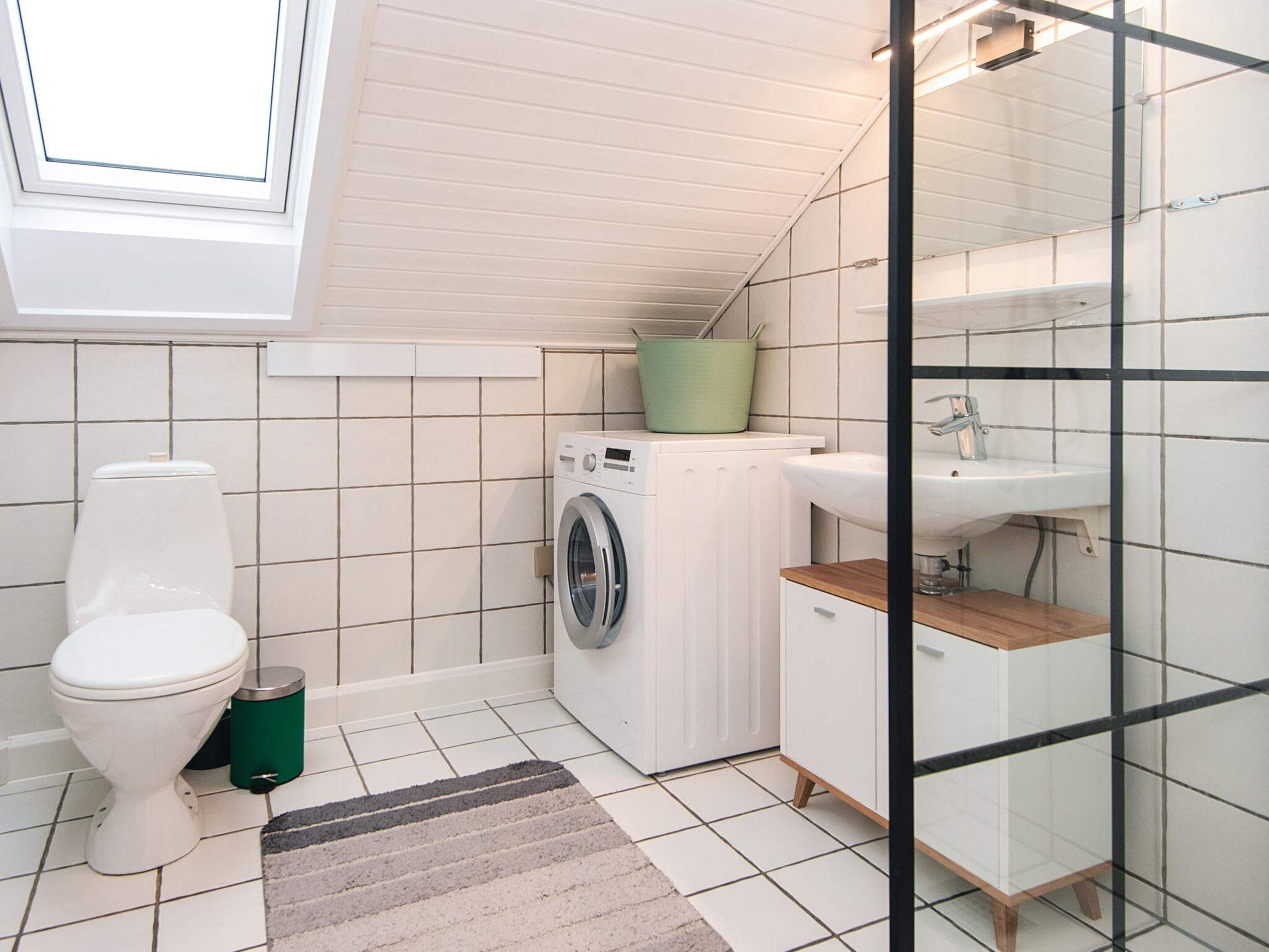 Ein kleines Badezimmer mit Toilette, Waschmaschine und Waschbecken.