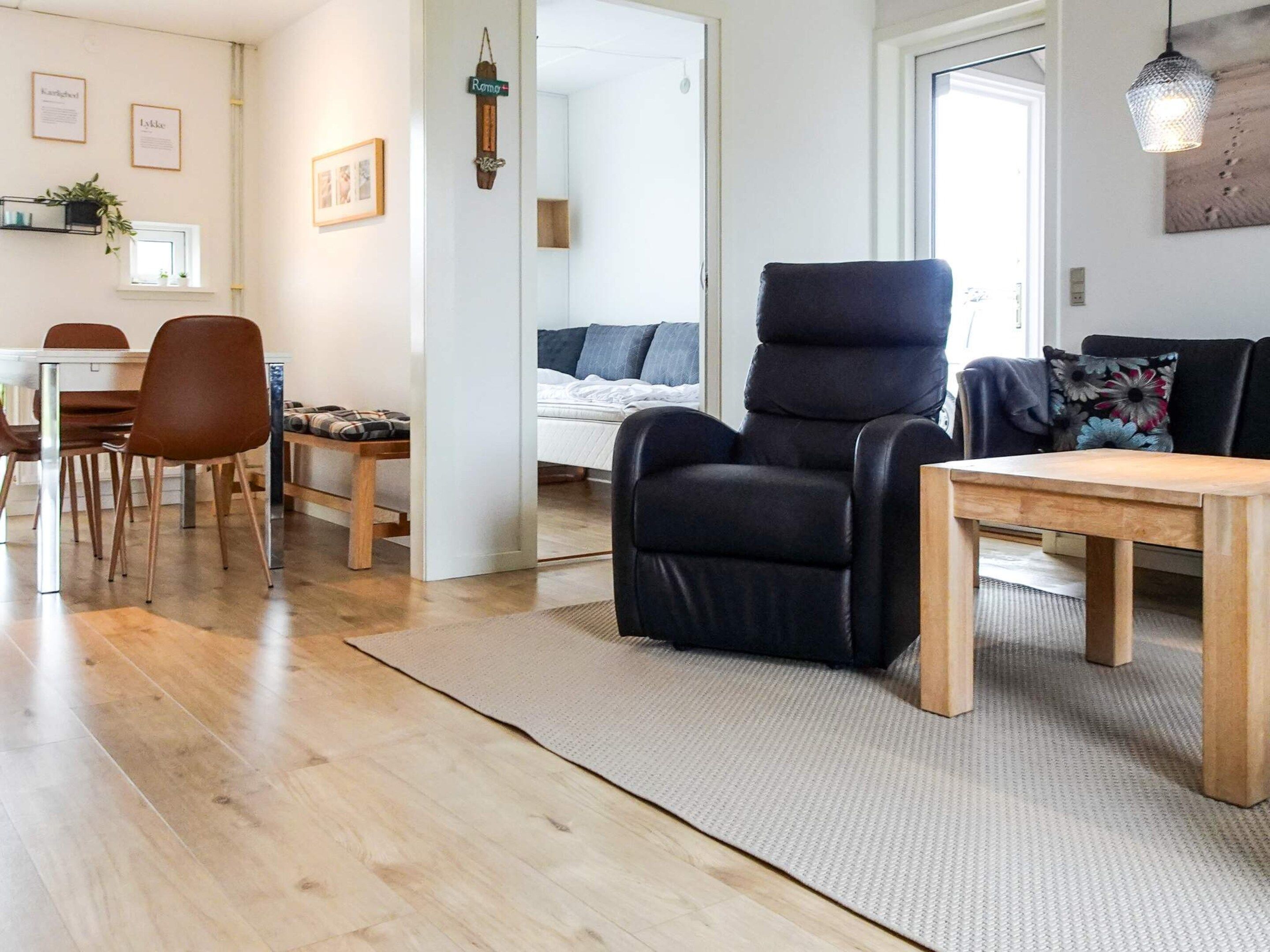 A modern living room with a black recliner, wooden dining table, and chairs.