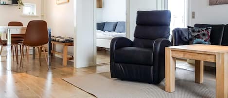 A modern living room with a black recliner, wooden dining table, and chairs.