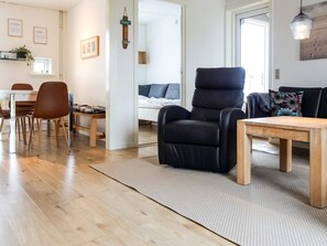 A modern living room with a black recliner, wooden dining table, and chairs.
