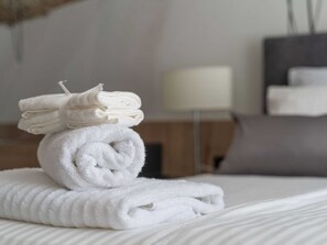 A neatly made bed with folded white towels stacked on top. - Apartments Villa Royale - Luxury One Bedroom Apartment With Terrace (Konavle)