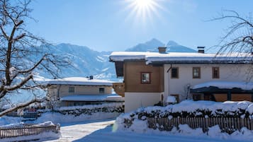 Ein schneebedecktes Dorf mit traditionellen Häusern, einem Holzzaun und Bergen im Hintergrund.