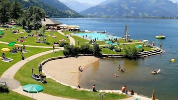 Ein Seehotel mit Schwimmbad, Liegestühlen und einer Rasenfläche mit Sonnenschirmen.