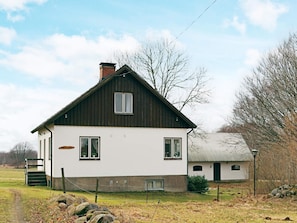 Une maison à deux étages, avec une façade blanche et un toit foncé.