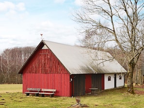 A red barn with a sloped roof, a bench, and a table in front. - 9 Person Holiday Home in Bastad (Bastad)
